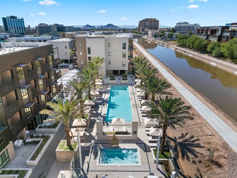 Exterior apartment complex with a pool and palm trees.