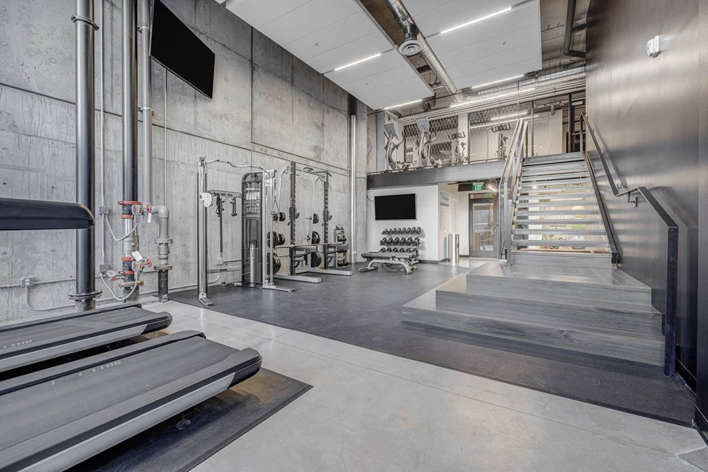 the lobby of a gym with stairs and a tv