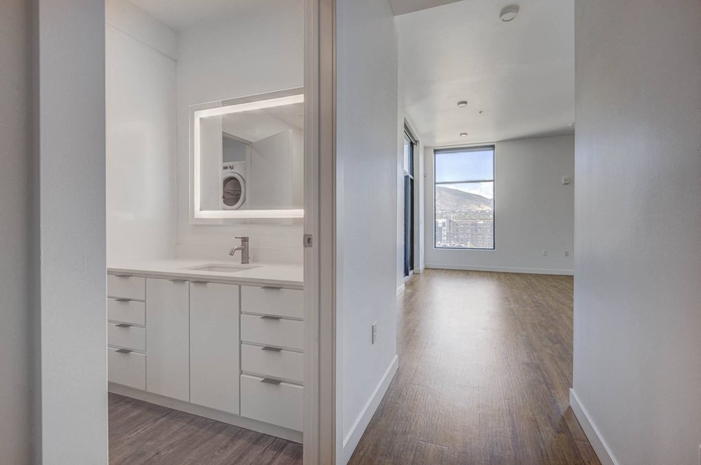 White finished bathroom leading into hallway with wood flooring