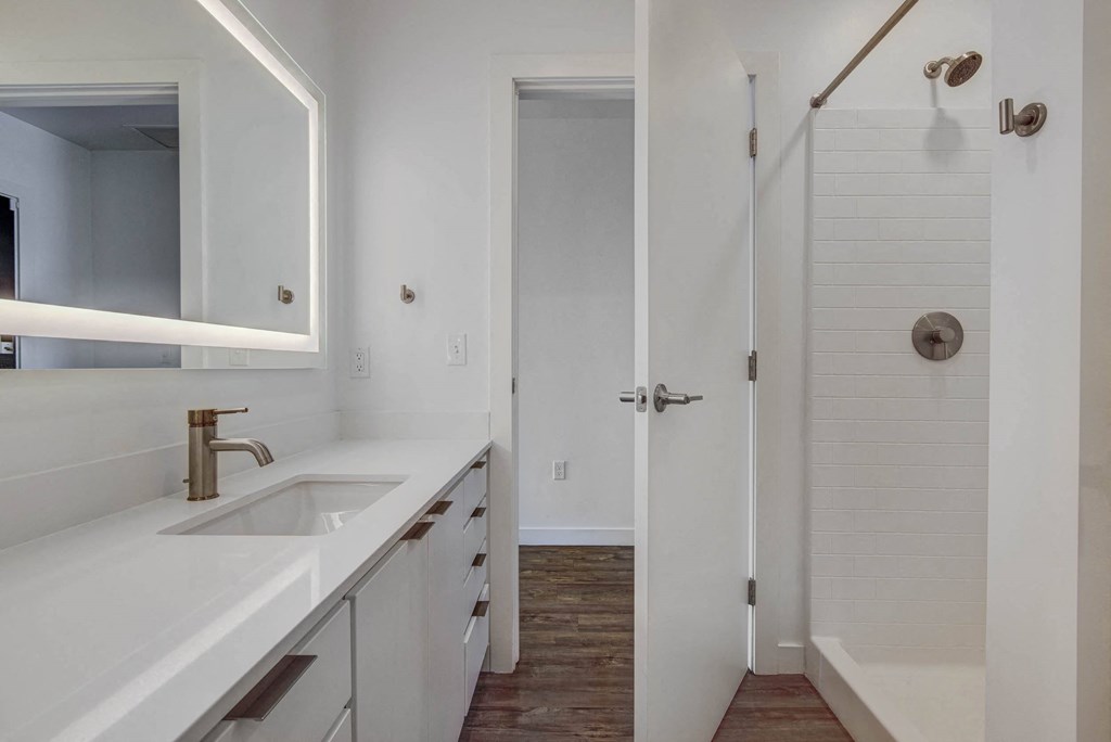 bathroom with fully lit mirror, standing shower and spacious countertops