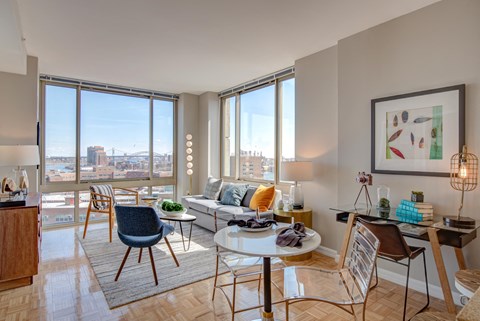 A living room with a couch, chairs, and a table with a view of the city.