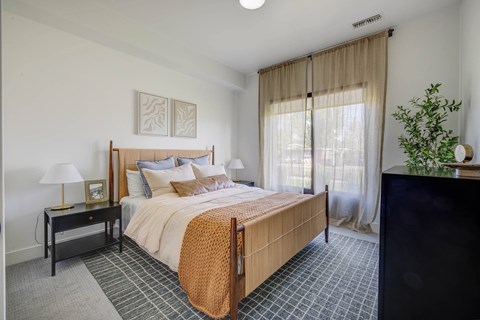 A bedroom with a large bed and a lamp on a nightstand.