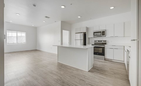 A modern kitchen with white cabinets and a wooden floor.