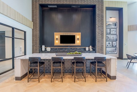 a large kitchen with a marble counter top and a bar with chairs
