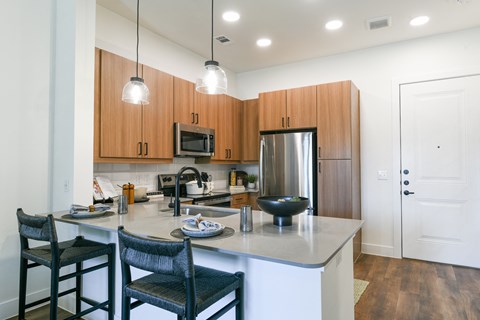 a kitchen with a large island with a counter top and chairs