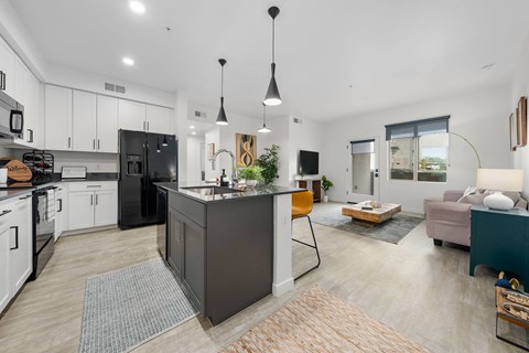 A modern kitchen with a black refrigerator and white cabinets.