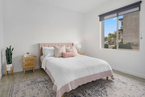 A bedroom with a large bed and a window overlooking a building.