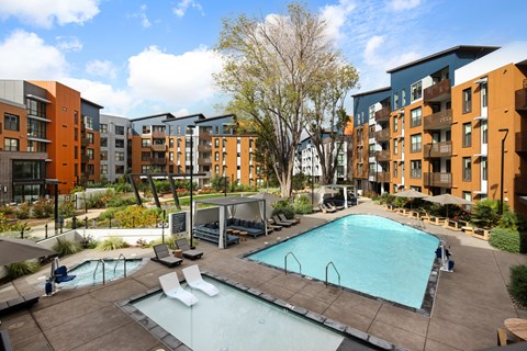 A large swimming pool surrounded by a wooden deck and lounge chairs.