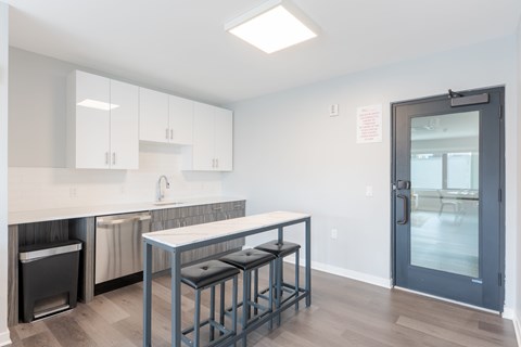 A kitchen with a white counter top and a black trash can.