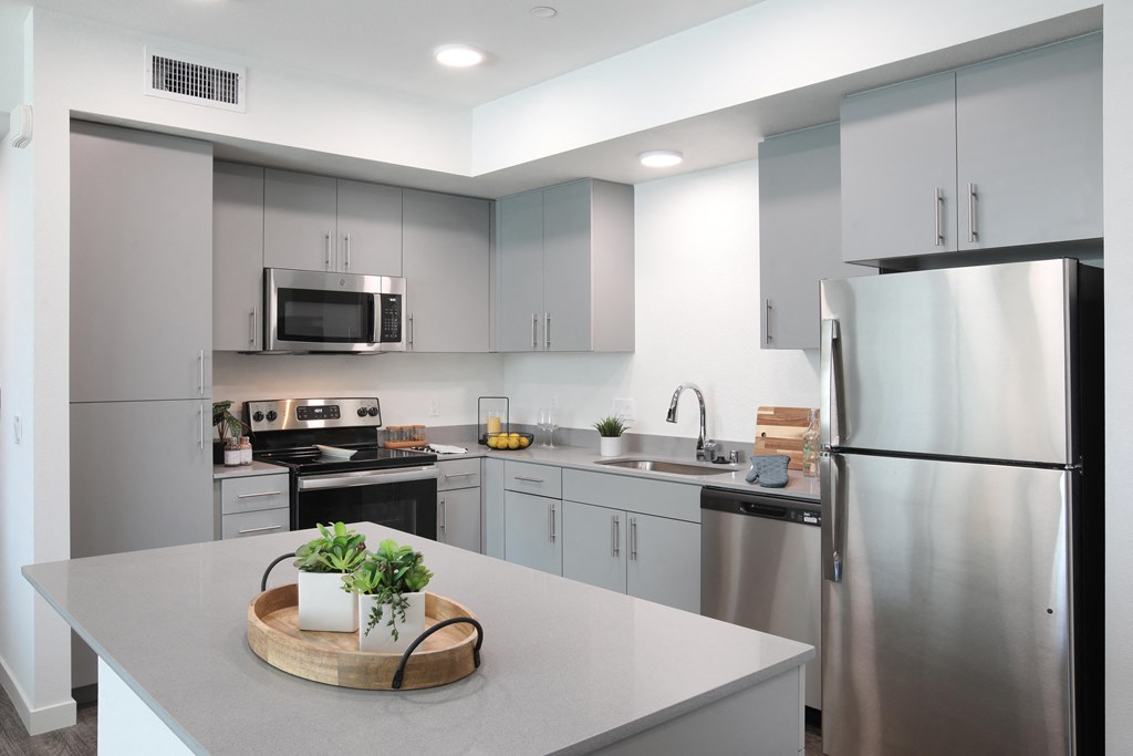 an open kitchen with stainless steel appliances and white countertops