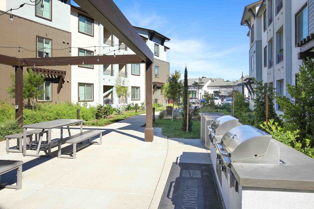 a patio with benches and picnic tables in front of a building