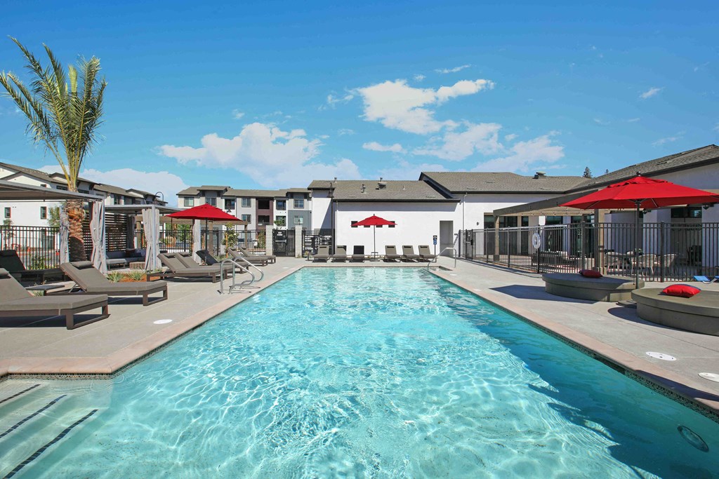a swimming pool with chairs and umbrellas next to a building