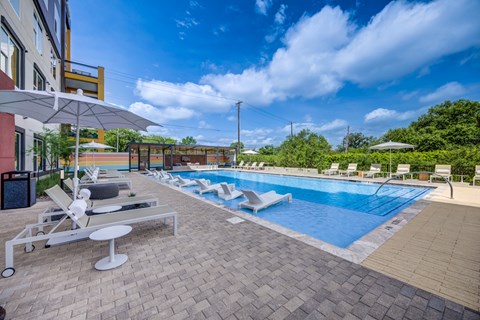 A large outdoor swimming pool with sun loungers and umbrellas.