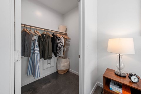a closet in a bedroom with a dresser and a lamp