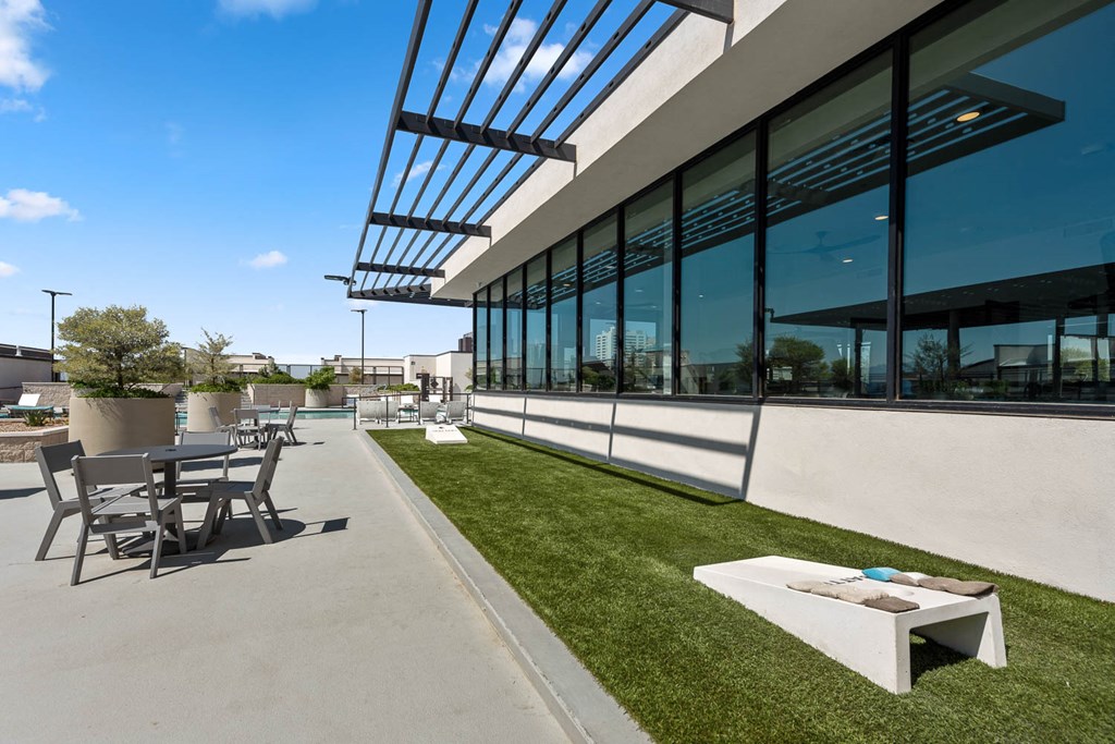 the outdoor patio of the building has tables and chairs and grass