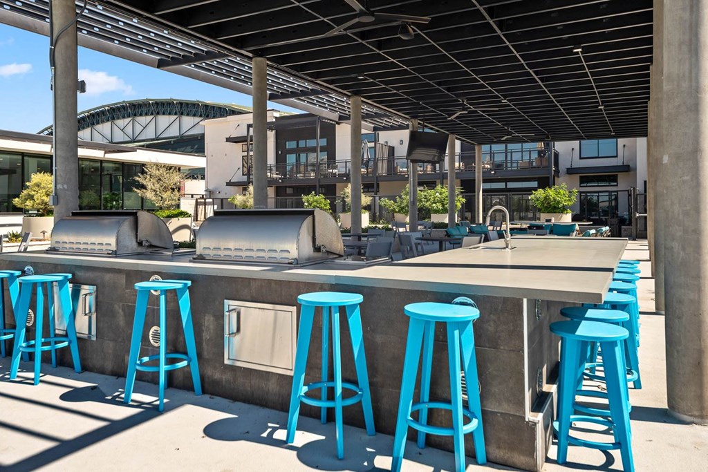 a bar with blue stools and chairs in front of a building
