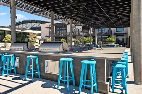 a bar with blue stools and chairs in front of a building