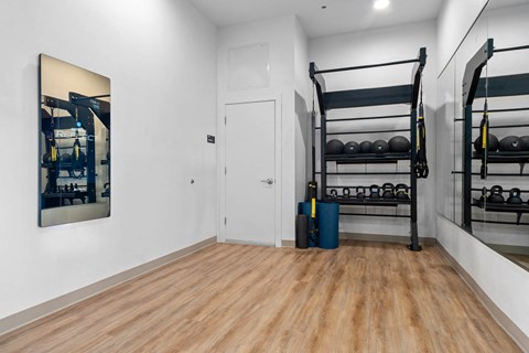 a room with white walls and wood floors and a black bunk bed