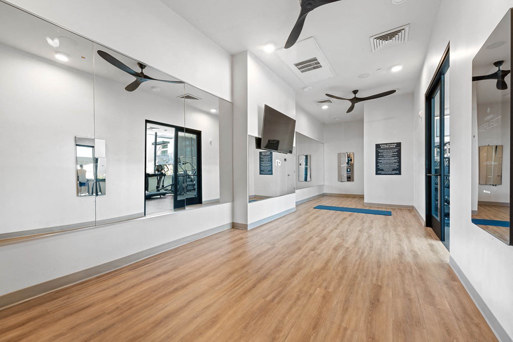 a large room with white walls and wood floors and mirrors