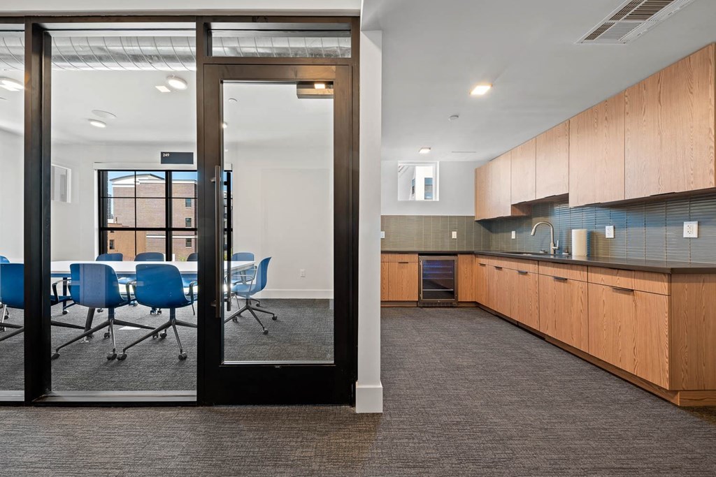 a conference room with a table and chairs and a kitchen