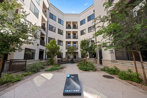an outdoor courtyard with a sign in front of an apartment building