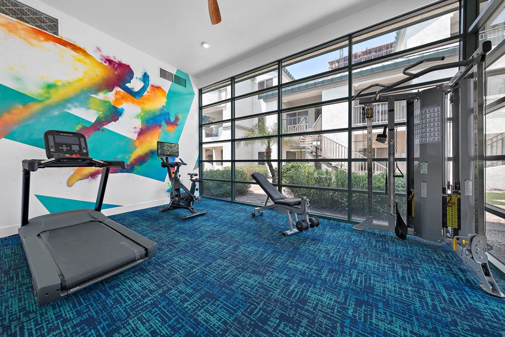 a workout room with floor to ceiling windows and a colorful mural