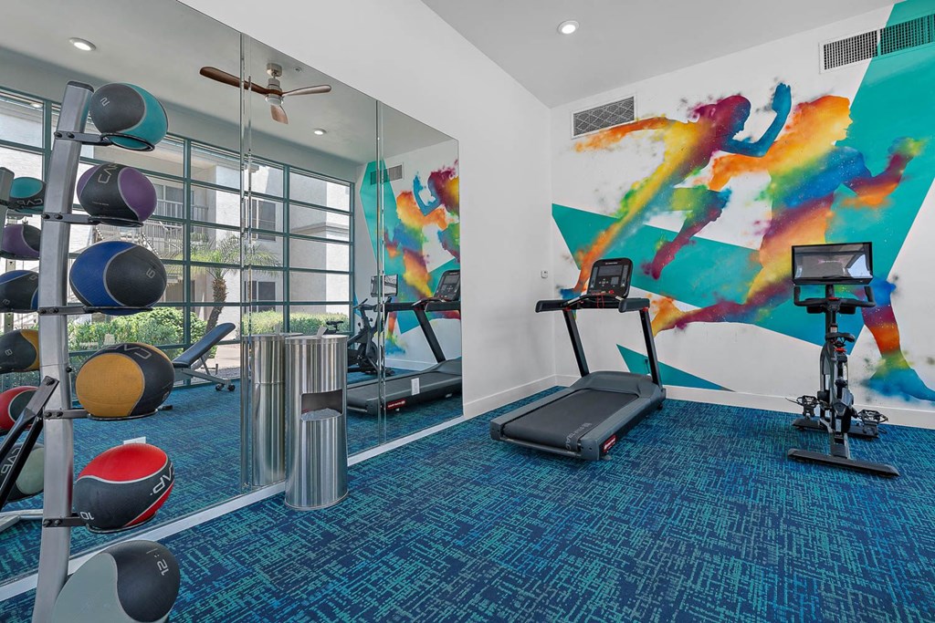 a gym with cardio equipment and a painting on the wall