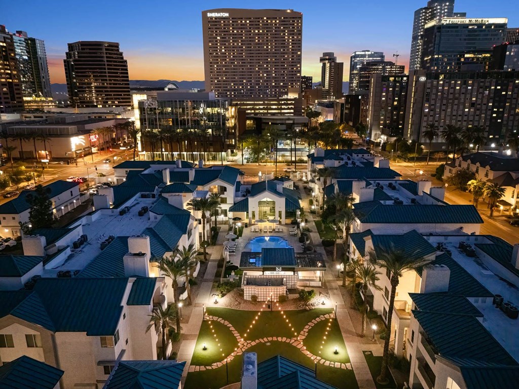 A cityscape at dusk with a lit-up building in the foreground.