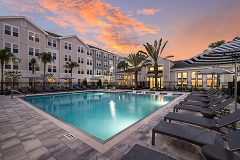 A large swimming pool surrounded by lounge chairs and palm trees.