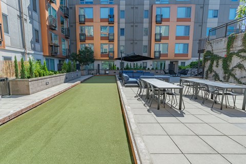 bocce area with tables and chairs and an apartment building in the background