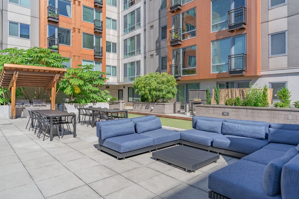 an outdoor lounge area with blue couches and tables and chairs