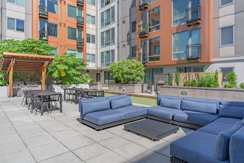 an outdoor lounge area with blue couches and tables and chairs