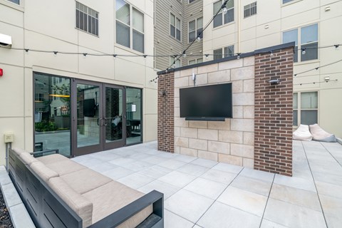 a patio with a couch and a tv in front of a building