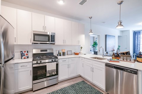 kitchen with white cabinets and stainless steel appliances at the enclave at woodbridge apartments in sugar land