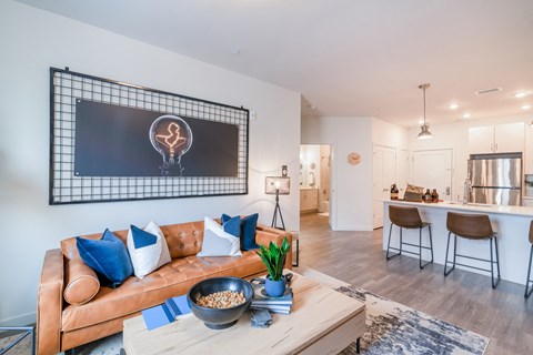 a living room with a brown leather couch and a coffee table with blue and white pillows