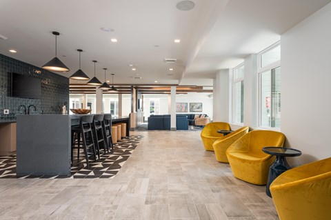 A modern kitchen with yellow chairs and a bar area.