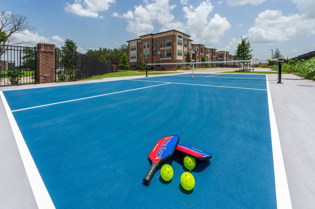 A blue tennis court with a red and blue toy racket and three yellow balls.