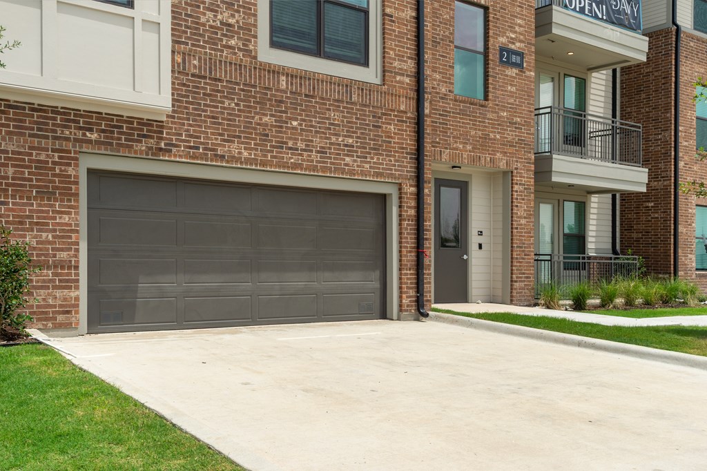 A brick building with a garage door and a balcony.