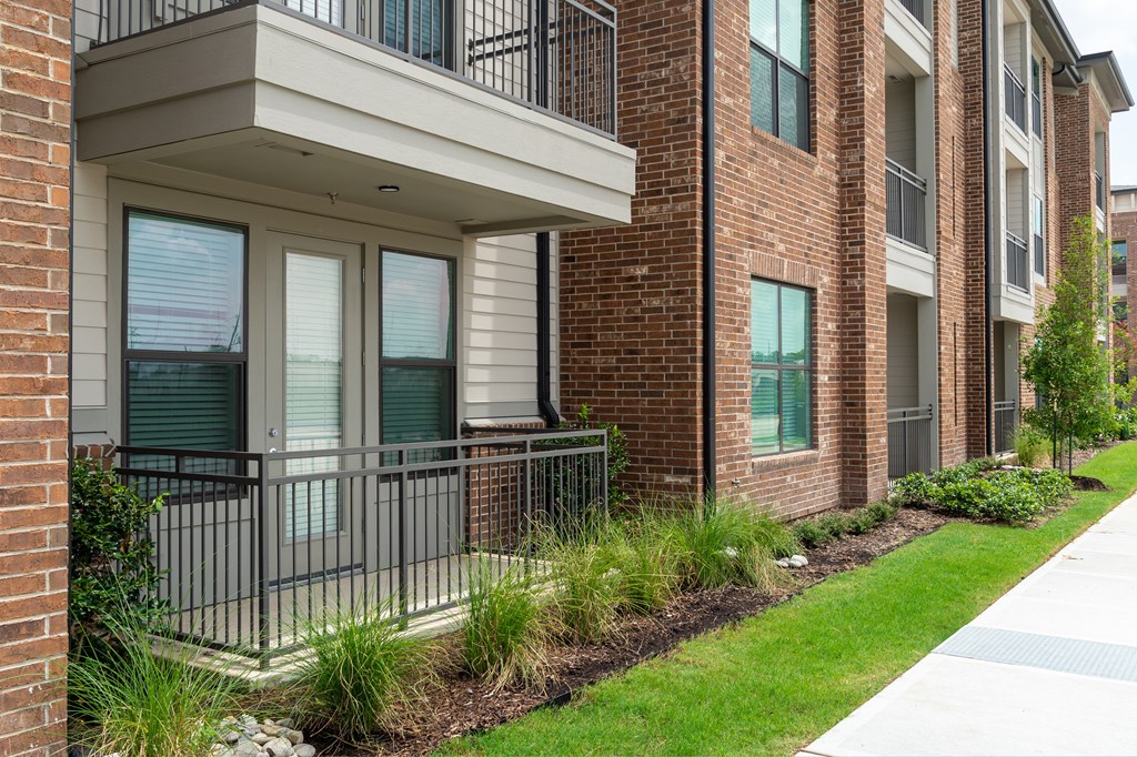 A brick building with a balcony and a metal railing.