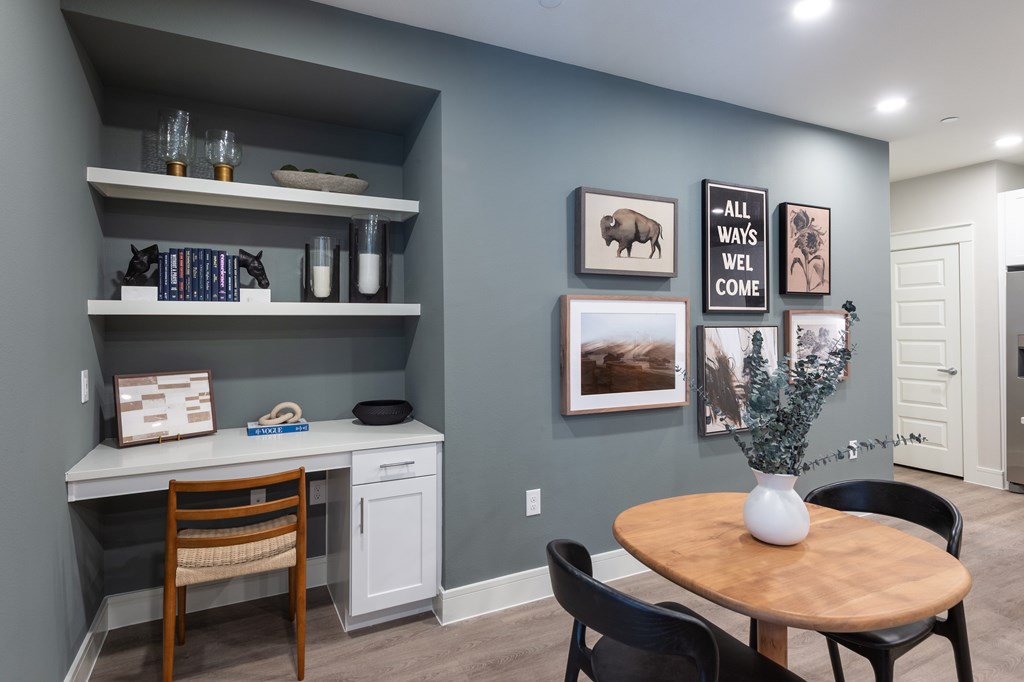 A room with a desk, chairs, and pictures on the wall.