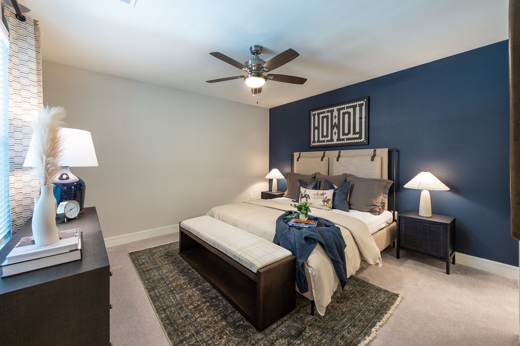 A bedroom with a bed, nightstand, and ceiling fan.