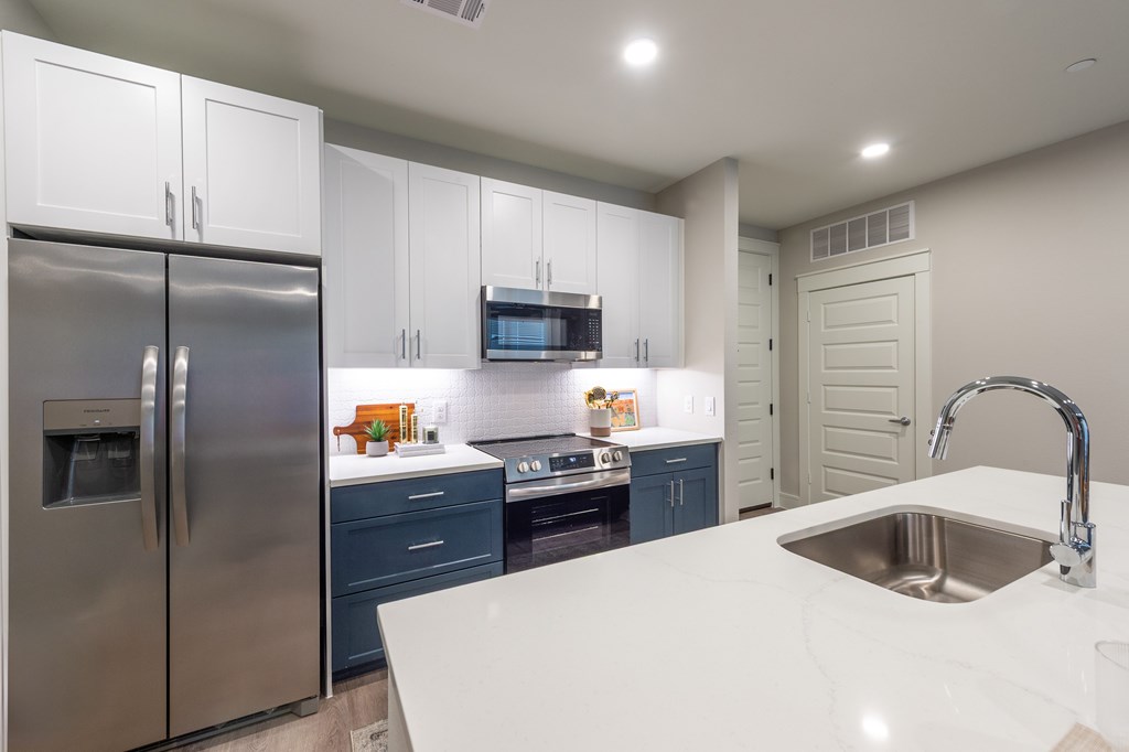 A modern kitchen with a stainless steel refrigerator and a white countertop.