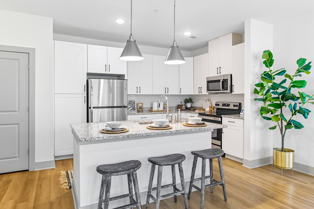 A kitchen with a white counter top and grey bar stools.
