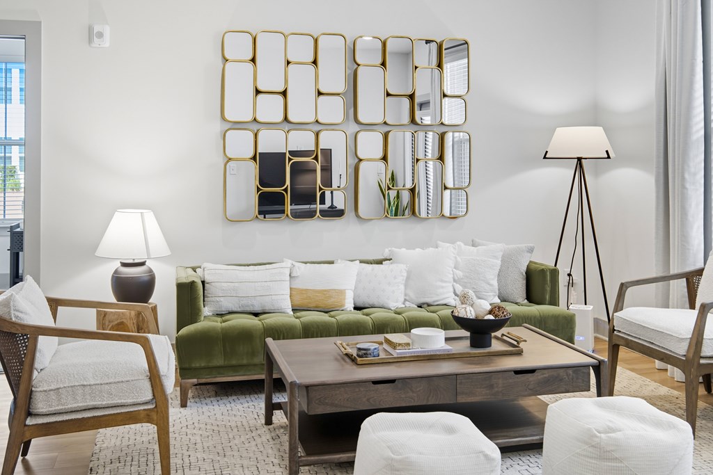 A modern living room with a green couch, a wooden coffee table, and a large mirror on the wall.
