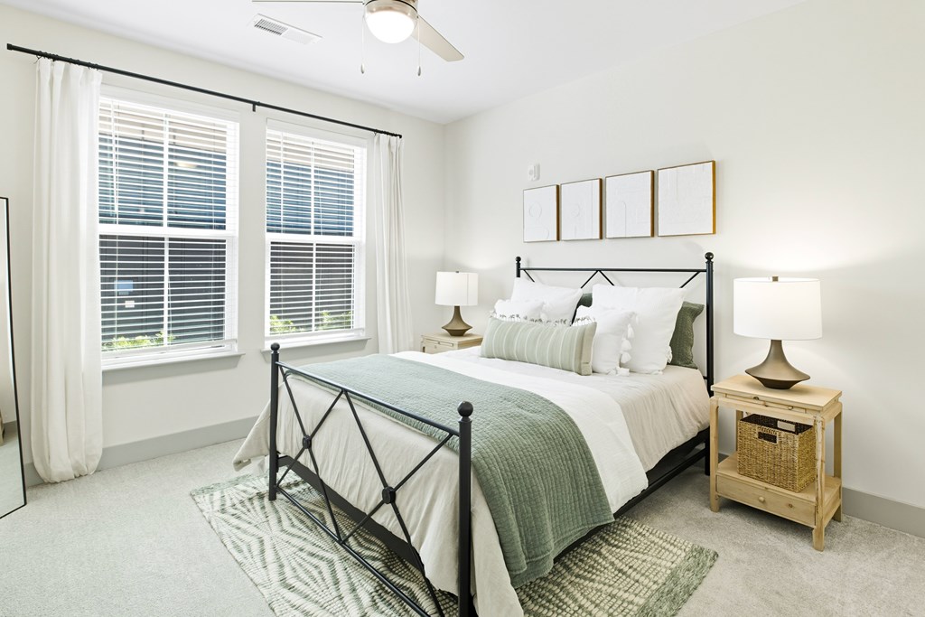 A bedroom with a bed, nightstand, and window with blinds.