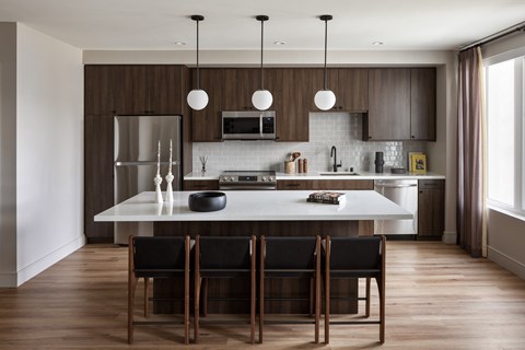 a kitchen with wooden cabinets and a white island with black chairs