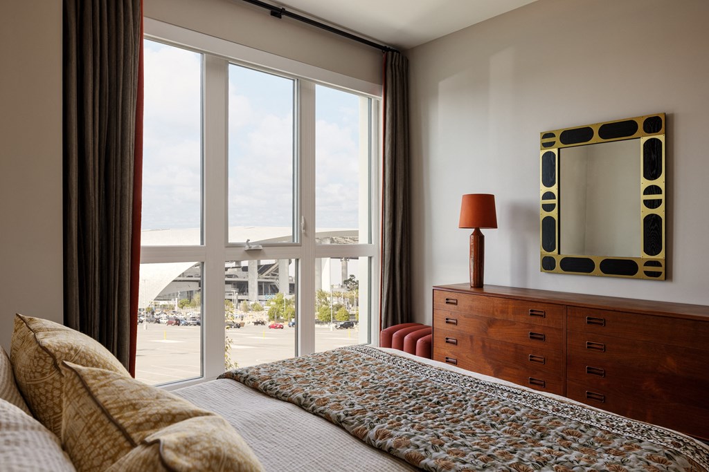 a bedroom with a large window and a bed and a dresser