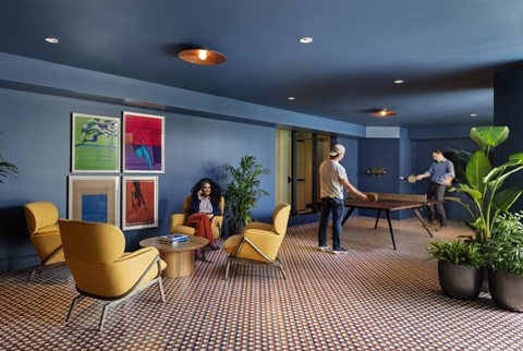 a group of people playing a game of ping pong in a room with blue