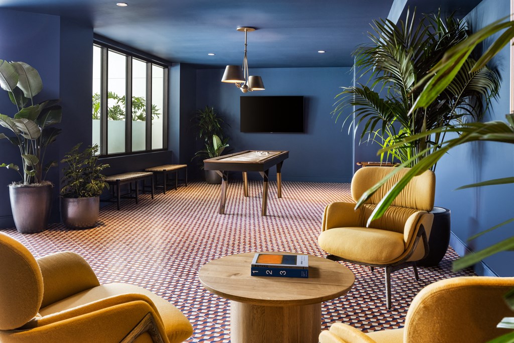 a living room with blue walls and yellow furniture and a pool table