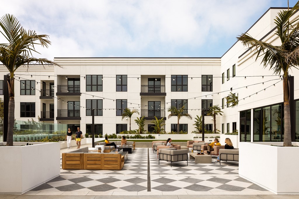 a large white building with a checkered courtyard with tables and chairs